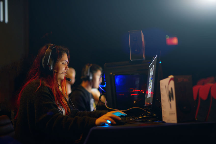 Female gamer with headset playing on a gaming pc