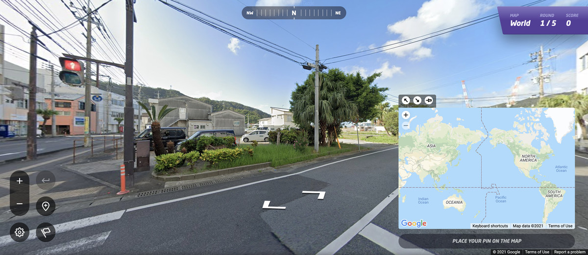 GeoGuessr'ın bir yolu, bir ağacı, bazı binaları ve elektrik hatlarını gösteren bir ekran görüntüsü. Google Sokak Görünümü kontrolleri, oyuncunun oyunu manipüle etmesine izin verir. Sağ alt köşedeki bir harita, oyuncuların nerede olduklarını tahmin etmelerini sağlar.